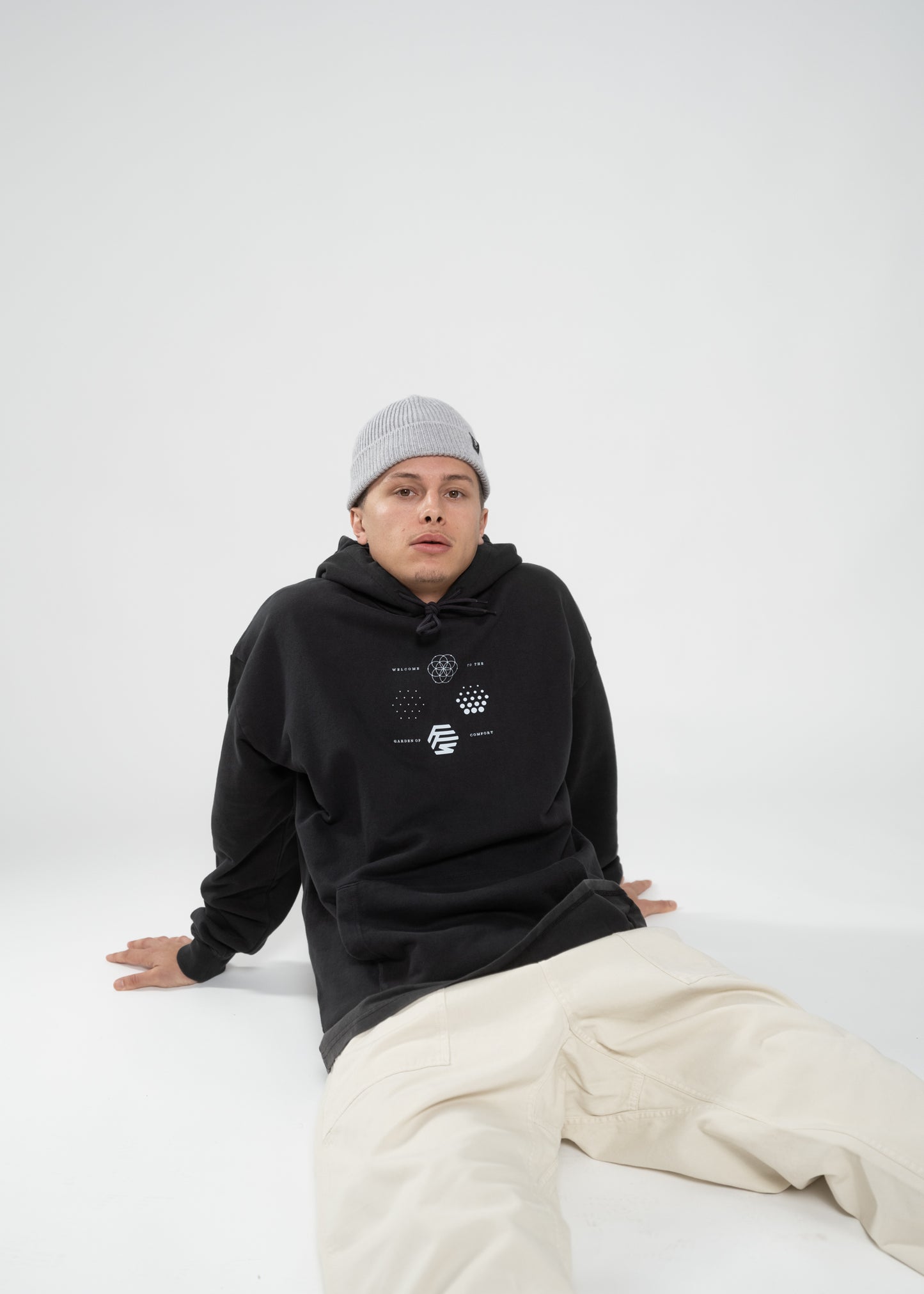 Flowers for Society garden hoodie vintage black side view worn by model Ben sitting on ground