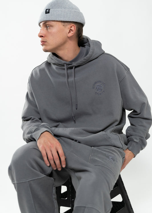 Flowers for Society basic hoodie washed grey front view worn by model Ben sitting on stool
