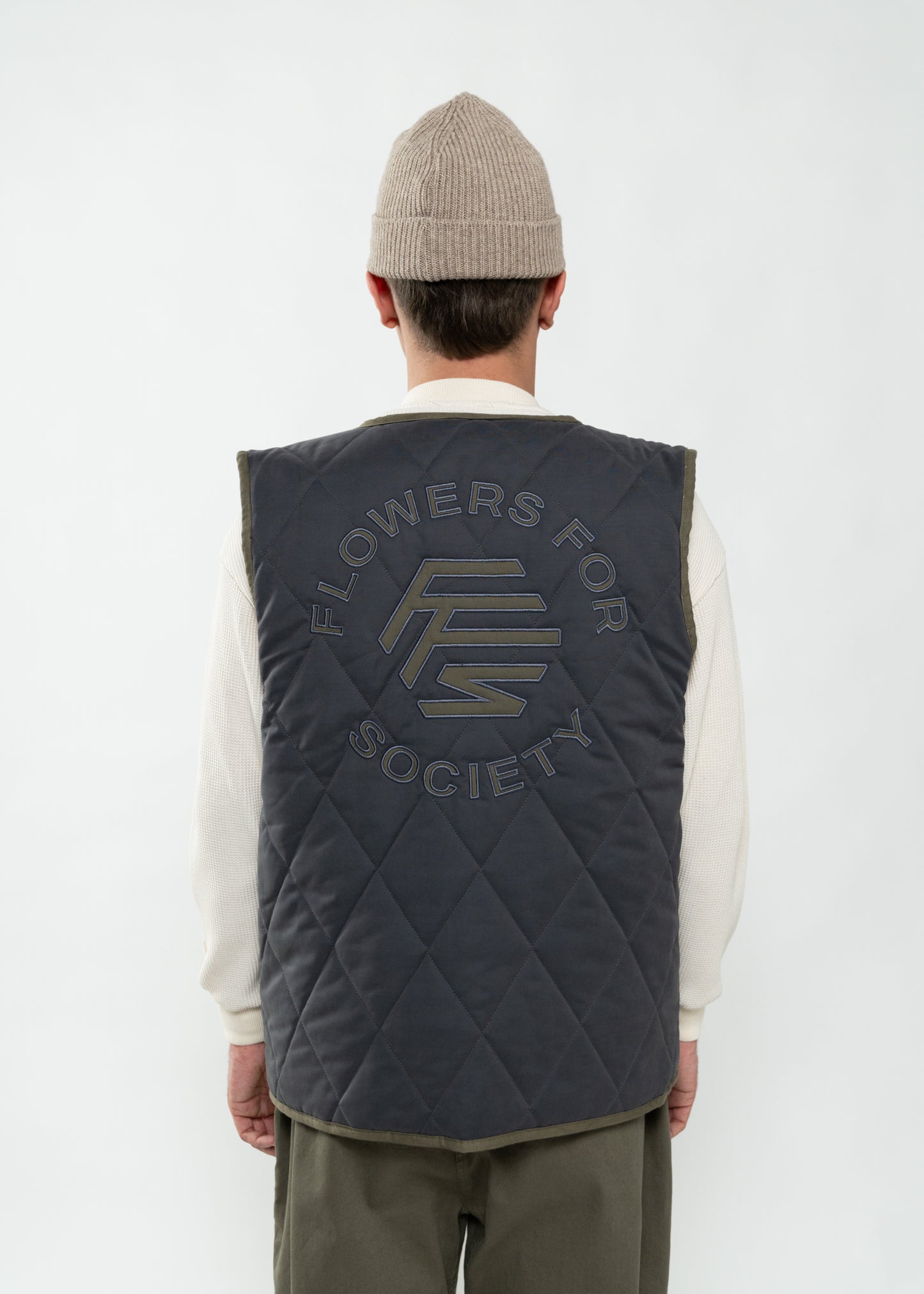 Flowers for Society reversible vest grey/olive backview worn by model Ben standing