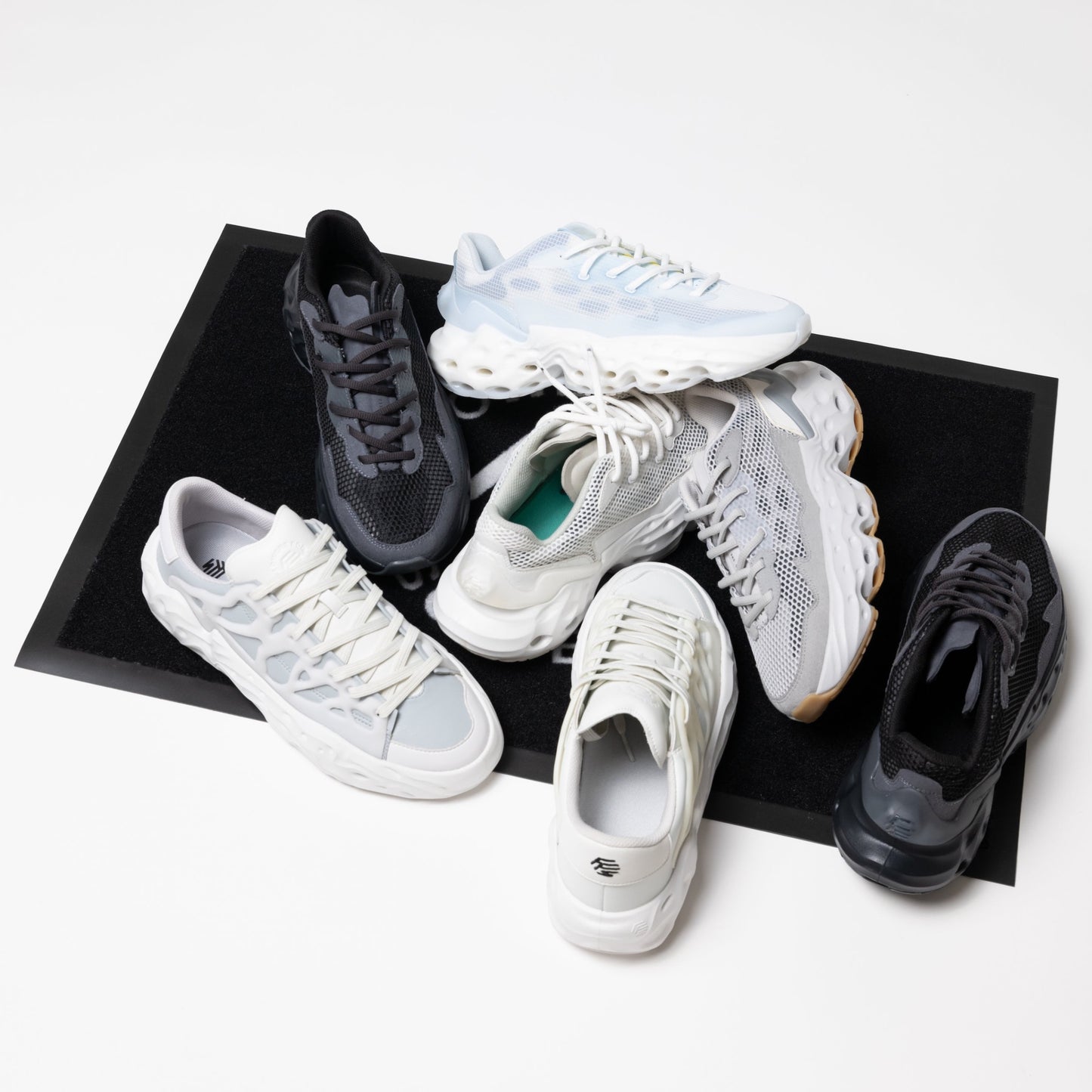 Flowers for Society door mat with a variety of different shoes from Flowers for Society randomly placed on it
