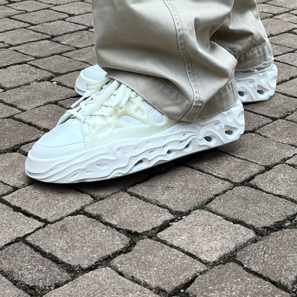 A campaign on-foot picture of the FFS Radicle Low OG worn by a person standing on paving stones