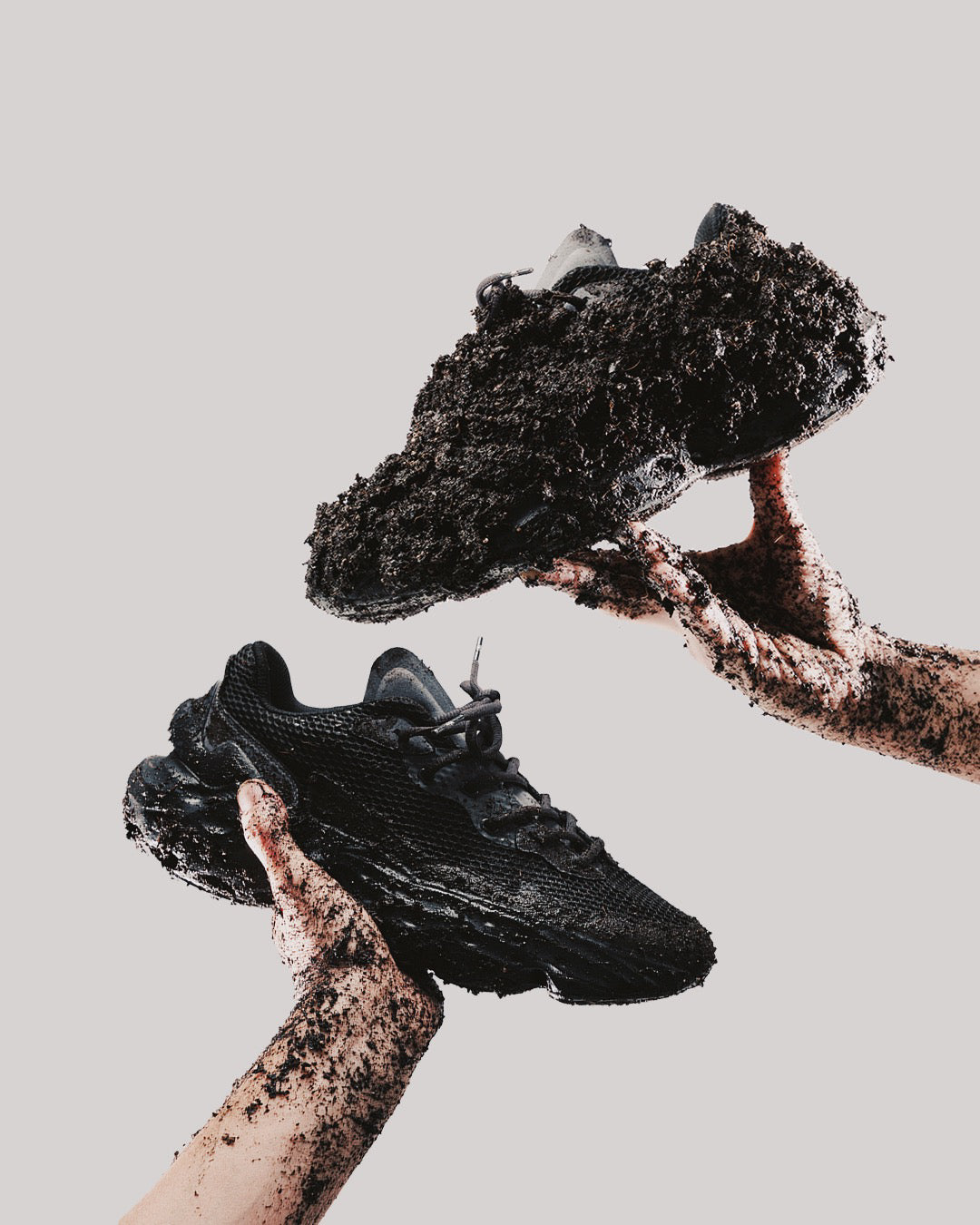Flowers for Society Sneaker Seed.One Black Mud black medial and lateral view held by hands covered in earth