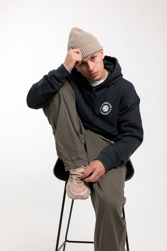 Flowers for Society basic chest print hoodie black front view worn by model Ben sitting on stool