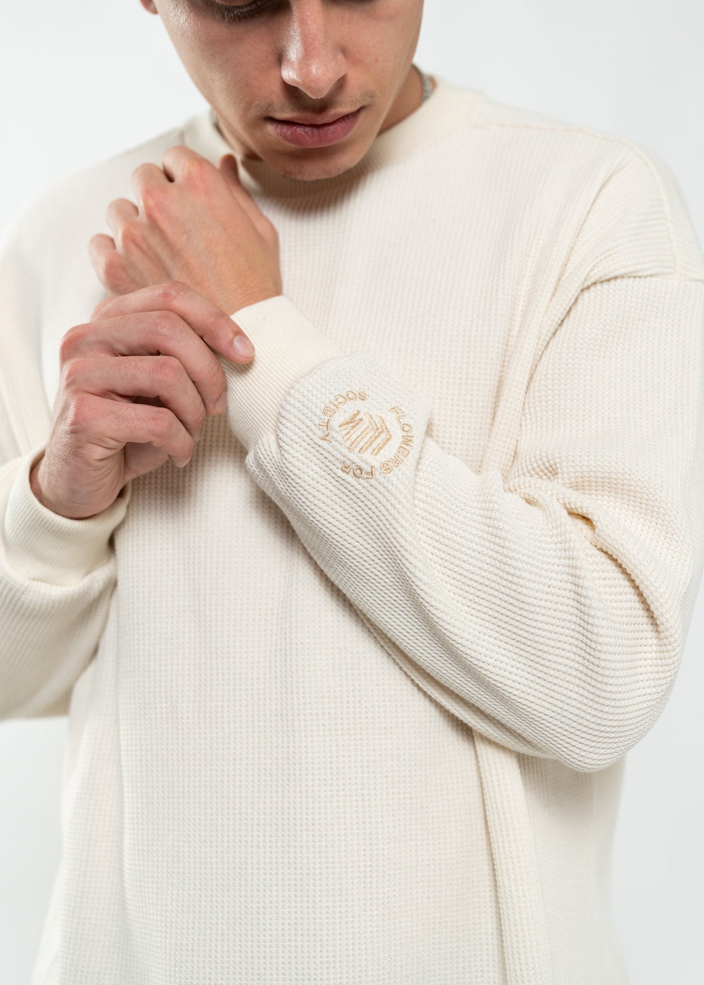 Flowers for Society waffle longsleeve off white side view detailed shot on Flowers for Society embroidered logo on the sleeve worn by model Ben standing