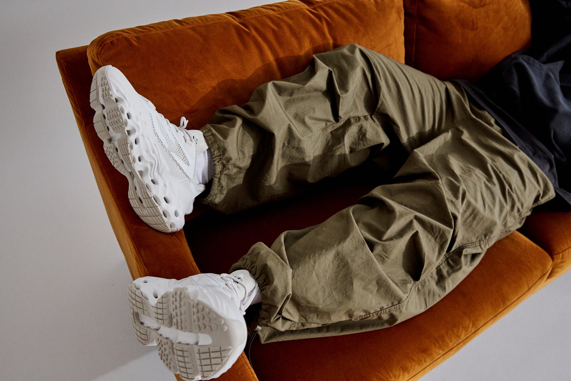 A model laying on a couch, wearing the shoe Seed.One in the colorway White Lily.